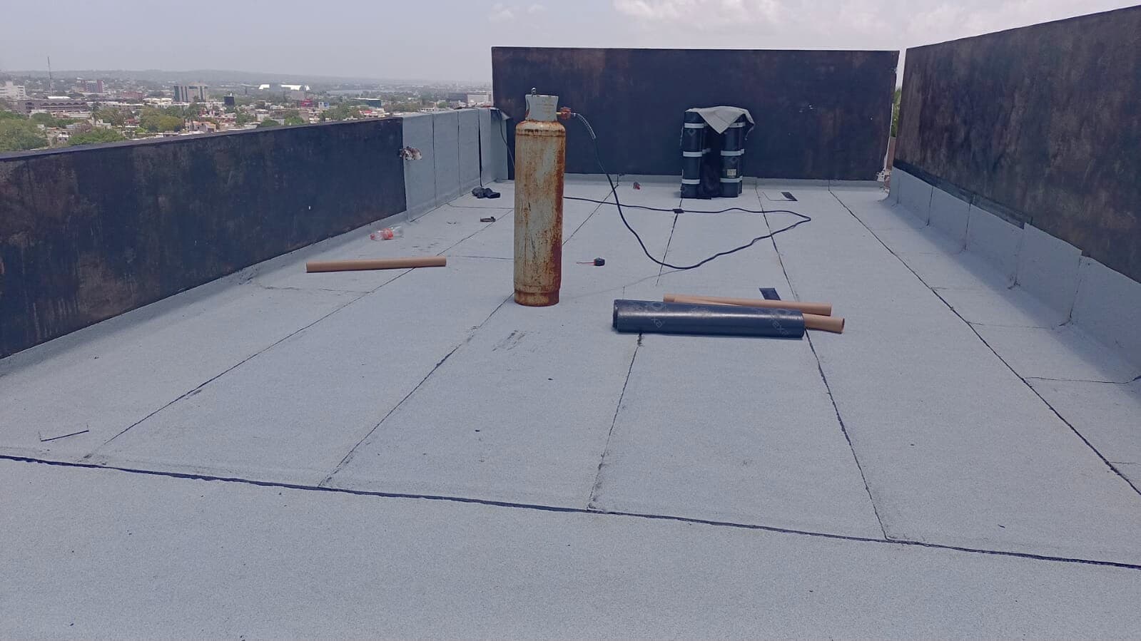 Avance de instalación de membrana gris con vista de la ciudad al fondo