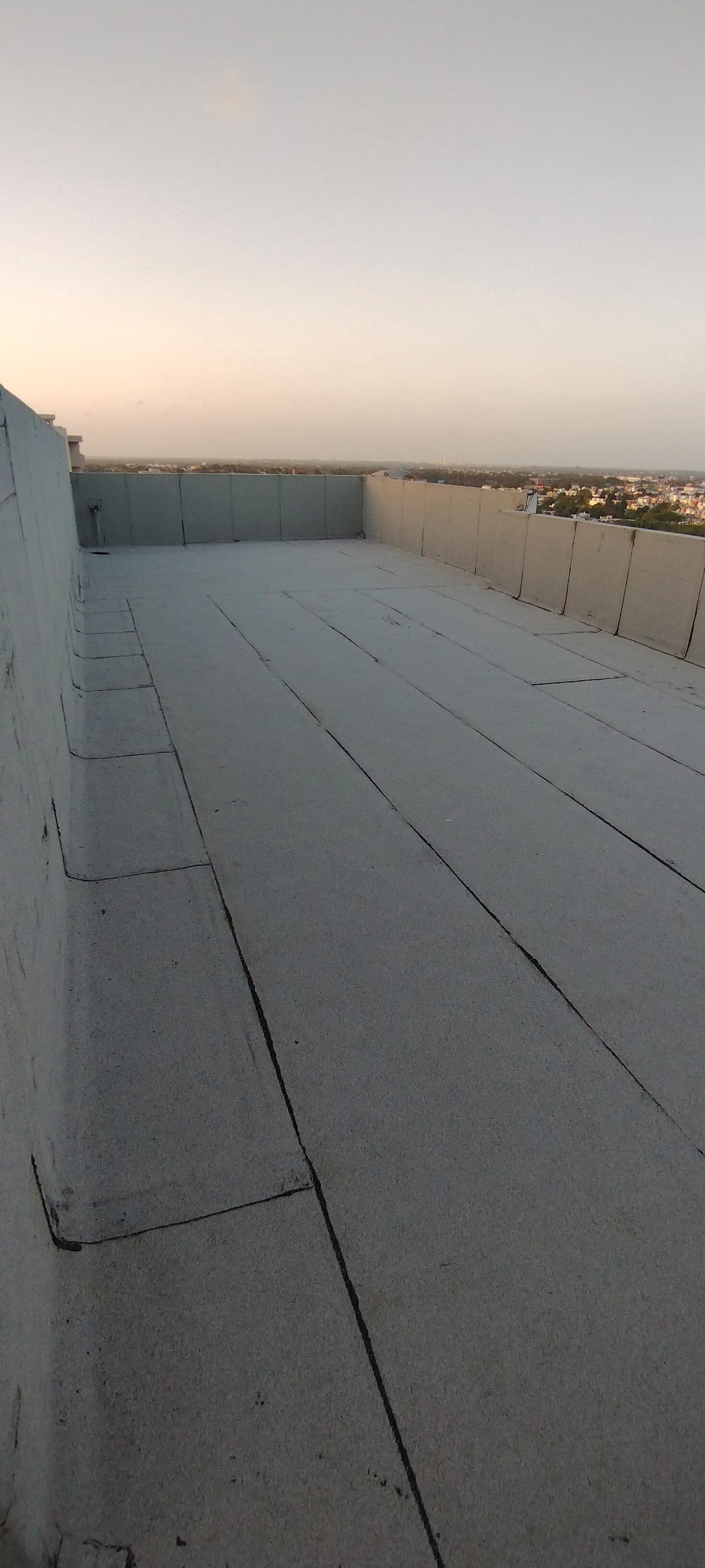 Azotea de edificio con membrana instalada al atardecer, ciudad visible abajo